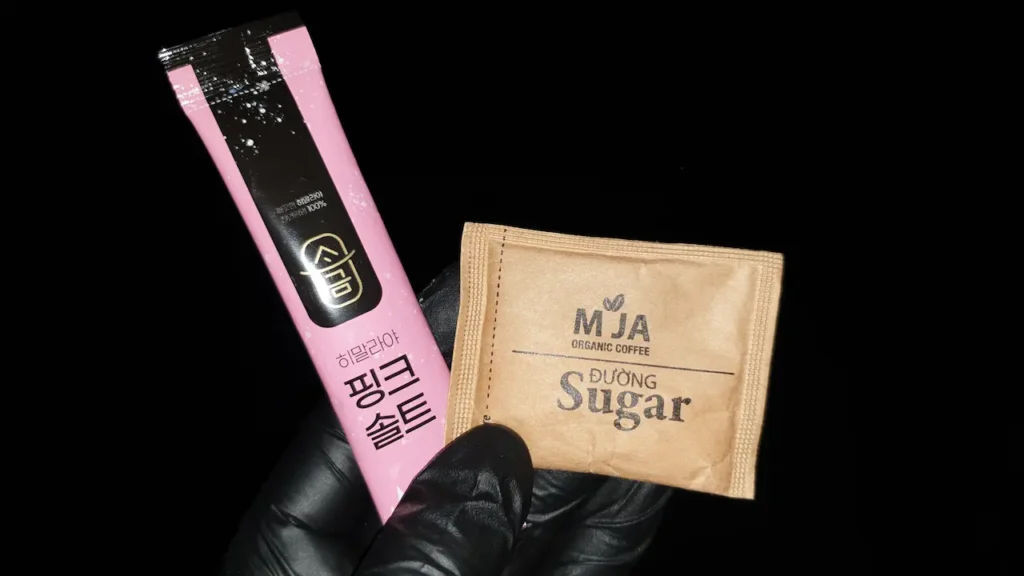 재난 가방 필수품인 분홍색 히말라야 핑크솔트 스틱과 MJA 유기농 설탕(Sugar) 봉지. 탈수 응급 처치용 ORS 재료