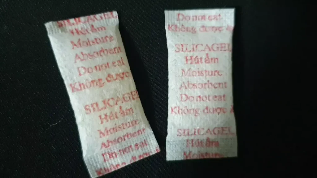 식품의 습기를 흡수하는 실리카겔(Silica Gel) 패킷 두 개가 나란히 놓여 있는 모습. 비상식량 보관 시 보조적으로 사용되는 습기 제거제의 모습