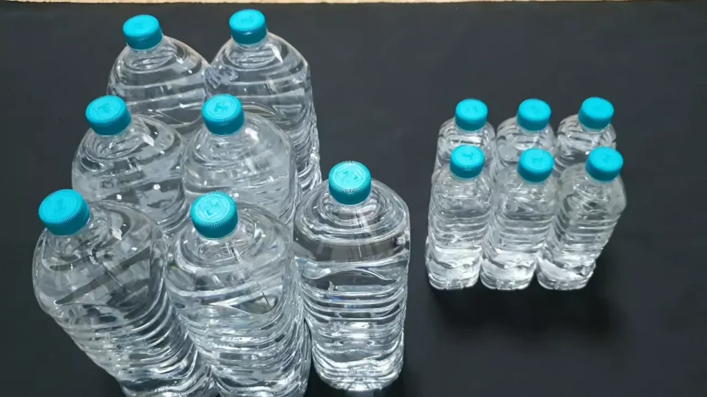 거점 비축용 2L 생수 7개와 이동 시 생존가방에 즉시 옮겨 담을 수 있는 500ml 생수병들이 함께 나열된 모습. 비상식량과 함께 7일간의 생존을 위해 최소 14리터의 물을 전략적으로 배분한 식수 비축 사진