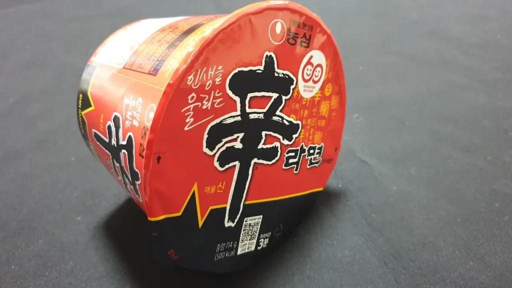 검은 배경 위에 놓인 신라면 큰사발 컵라면. 재난 상황 시 매운맛이 신체에 주는 부담과 물 소비 문제 등 선택받지 못한 논리적 이유를 분석하는 이미지
